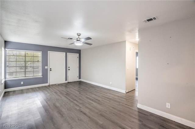 unfurnished living room featuring baseboards, dark wood-type flooring, and a ceiling fan