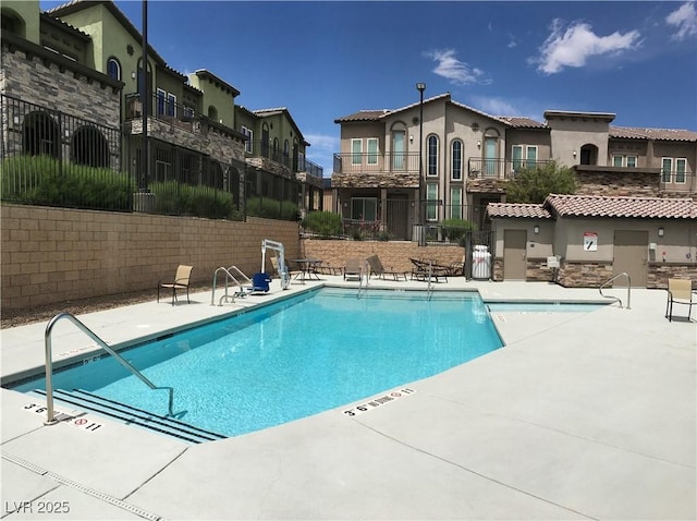 pool featuring a patio area, fence, and a residential view