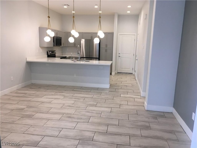 kitchen featuring a peninsula, a sink, light countertops, appliances with stainless steel finishes, and gray cabinetry