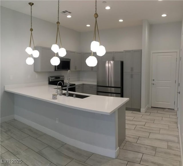 kitchen with stainless steel appliances, gray cabinetry, visible vents, a peninsula, and light countertops