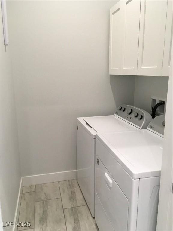 washroom with washing machine and clothes dryer, baseboards, and cabinet space