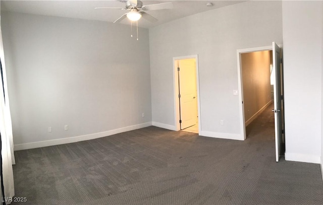 unfurnished room with dark colored carpet, baseboards, and a ceiling fan