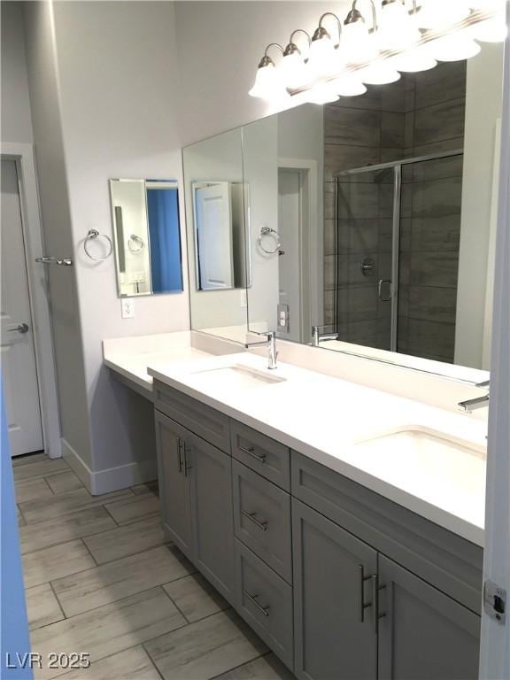 bathroom with double vanity, baseboards, a shower stall, and a sink