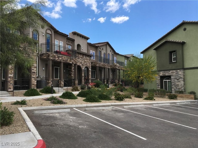 view of building exterior featuring uncovered parking and central AC