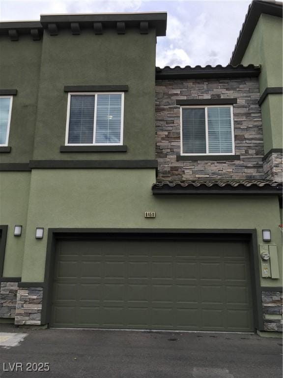 exterior space featuring stone siding, stucco siding, and an attached garage