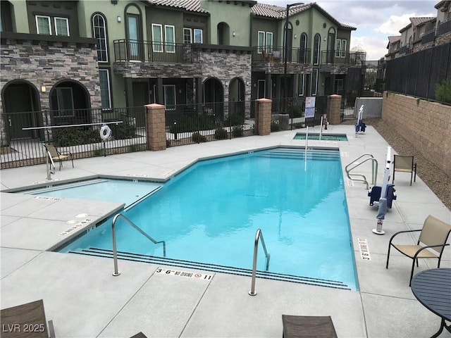 pool with a community hot tub, fence, and a patio