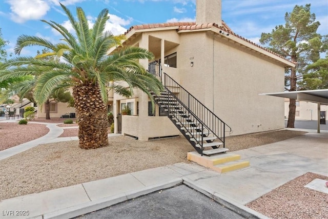 1112 Observation Dr Unit 201, Las Vegas, NV 89128 - view of side of property with a chimney, stairs, stucco siding, and a tiled roof