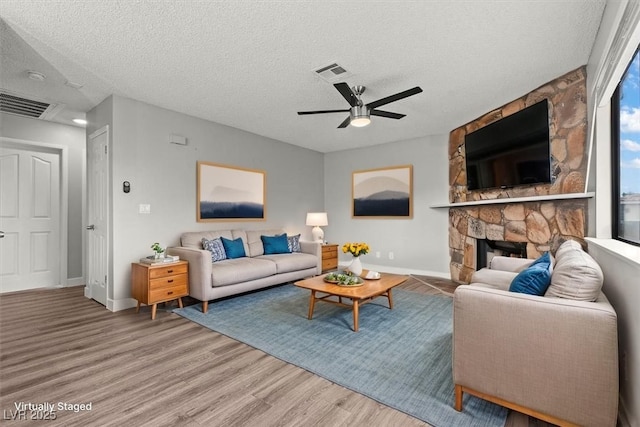 1112 Observation Dr Unit 201, Las Vegas, NV 89128 - living area with wood finished floors, a ceiling fan, a textured ceiling, and a stone fireplace
