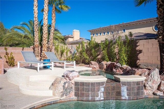 view of swimming pool featuring a hot tub, fence, and a patio