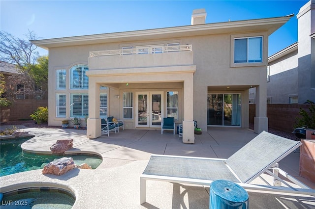 rear view of house with french doors, a patio, fence, and an in-ground hot tub
