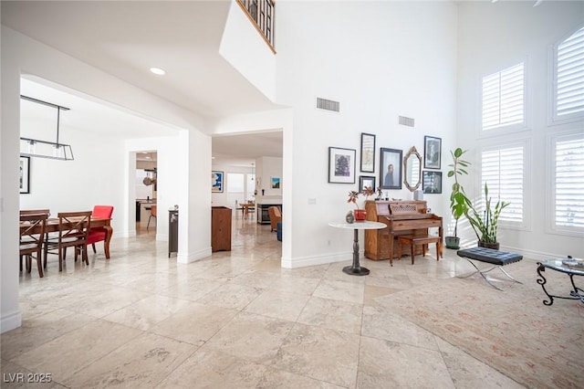foyer entrance featuring baseboards and a towering ceiling