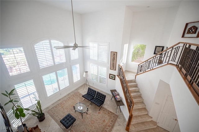 tiled entryway with high vaulted ceiling, stairs, baseboards, and ceiling fan