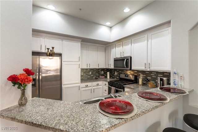 20 E Serene Ave Unit 111, Las Vegas, NV 89123 - kitchen with stainless steel appliances, decorative backsplash, a peninsula, white cabinetry, and recessed lighting