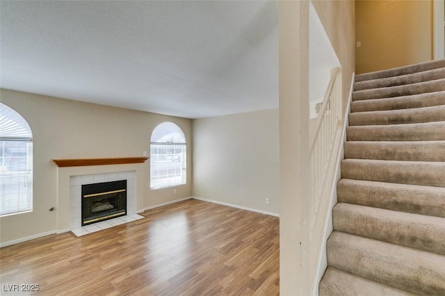 7732 Almeria Ave, Las Vegas, NV 89128 - unfurnished living room with wood finished floors, stairway, a tile fireplace, and baseboards