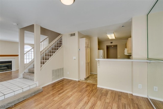 7732 Almeria Ave, Las Vegas, NV 89128 - unfurnished living room with light wood-style floors, stairs, a fireplace, and baseboards