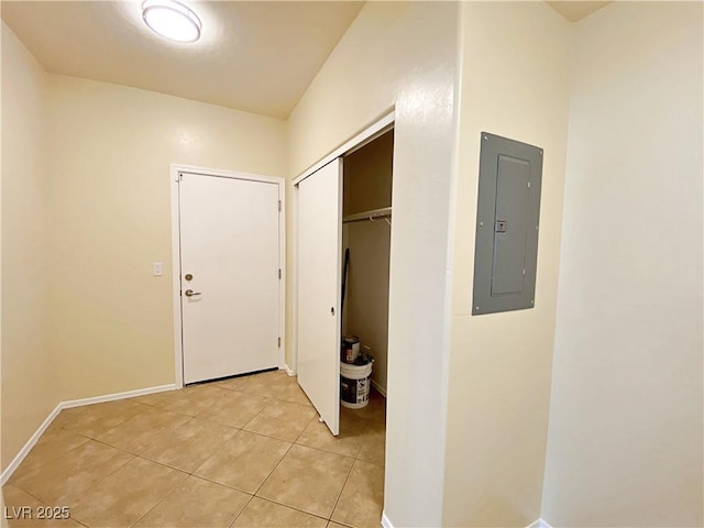 hall featuring electric panel, light tile patterned flooring, and baseboards