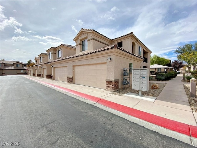 view of home's exterior with stucco siding, mail area, a residential view, stone siding, and an attached garage