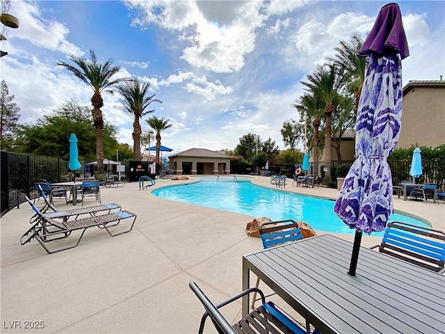 community pool with a patio area, fence, and outdoor dining area