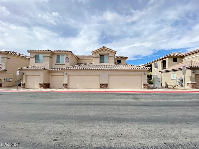 mediterranean / spanish-style home with stucco siding, a tile roof, and stone siding