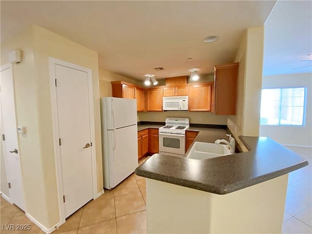 kitchen with white appliances, dark countertops, light tile patterned floors, and a peninsula