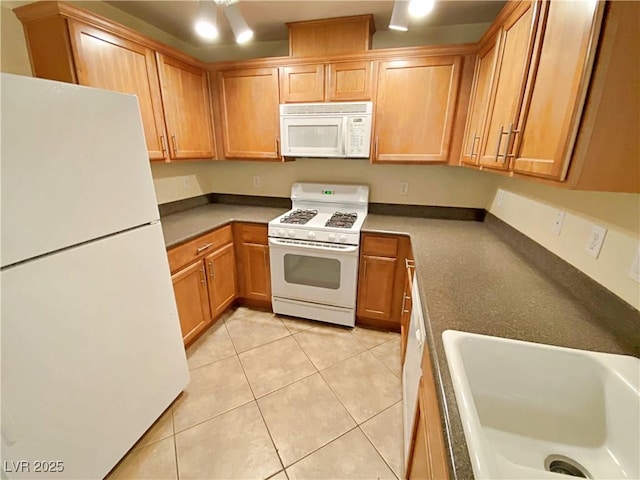 kitchen featuring white appliances, a sink, and light tile patterned flooring