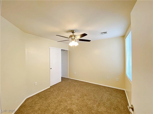 empty room with carpet, a ceiling fan, and baseboards