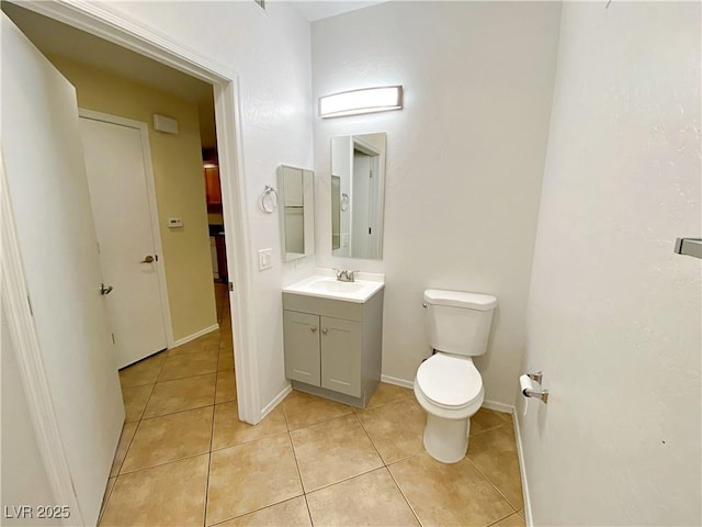 half bathroom featuring tile patterned flooring, toilet, vanity, and baseboards