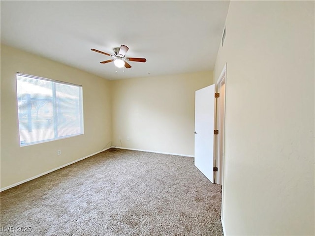 carpeted spare room featuring a ceiling fan and baseboards