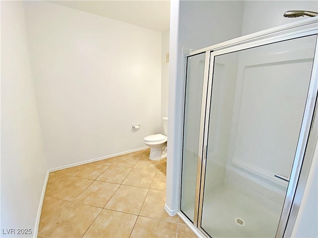 bathroom with tile patterned floors, toilet, a stall shower, and baseboards