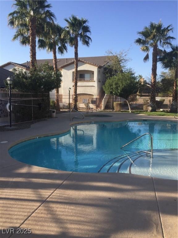 community pool with fence and a patio area