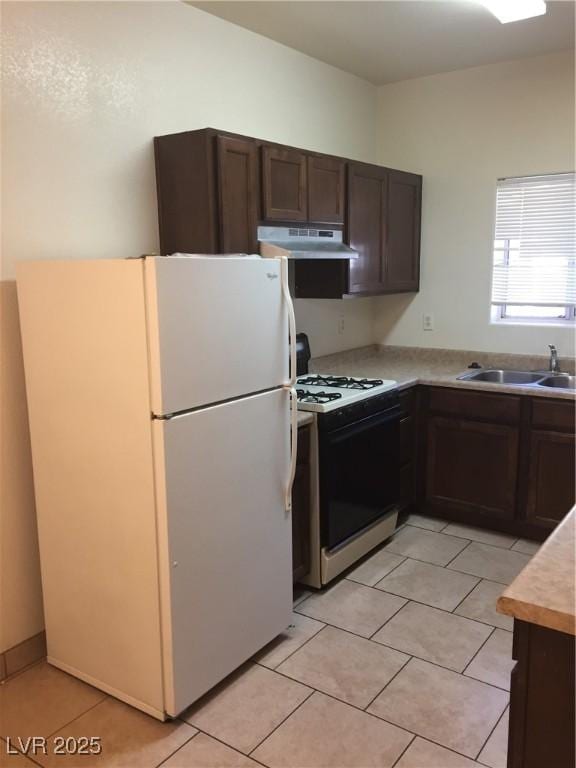 kitchen with white appliances, under cabinet range hood, light countertops, dark brown cabinets, and light tile patterned floors