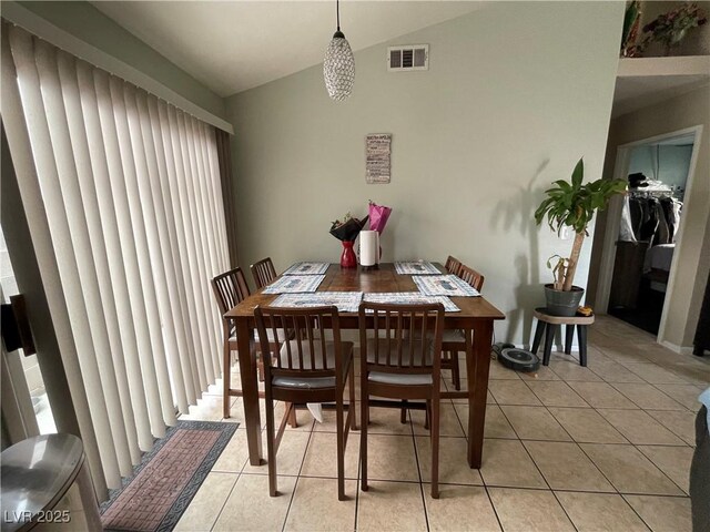 dining space with light tile patterned flooring and lofted ceiling