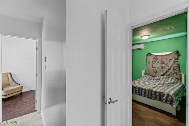 hall with a wall mounted AC, wood finished floors, and baseboards