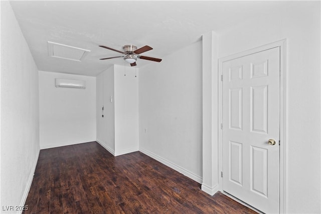 empty room with a wall mounted air conditioner, wood finished floors, baseboards, attic access, and ceiling fan