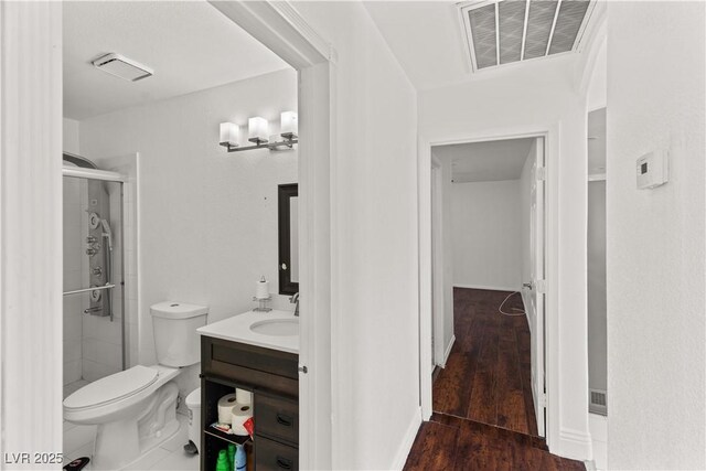 full bath with toilet, a stall shower, vanity, and wood finished floors