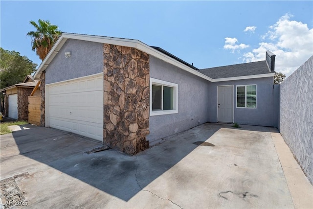 view of side of property with stone siding, stucco siding, driveway, and a garage