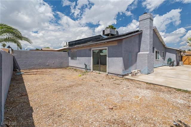 back of property with a fenced backyard, a patio, stucco siding, and a chimney