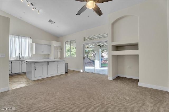 kitchen featuring vaulted ceiling, ceiling fan, baseboards, light countertops, and light colored carpet