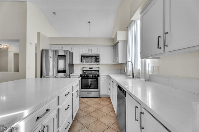 kitchen featuring stainless steel appliances, a sink, light countertops, white cabinets, and lofted ceiling