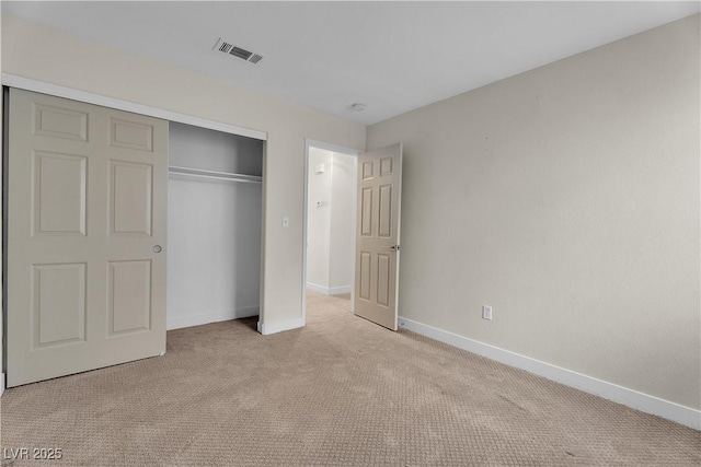 unfurnished bedroom featuring light colored carpet, a closet, and baseboards