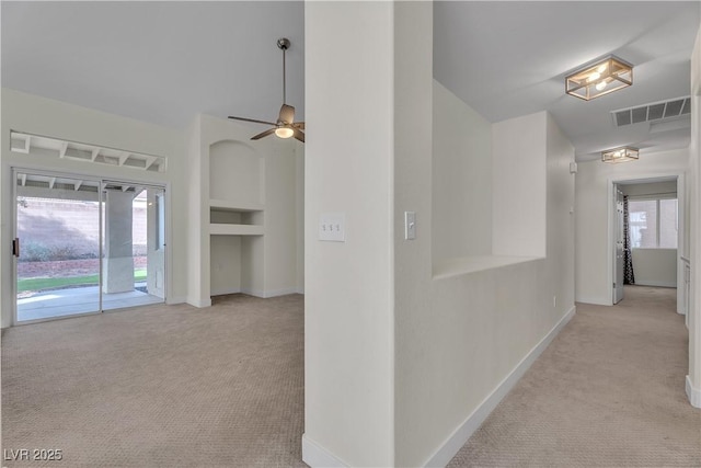 hall featuring light carpet, baseboards, and plenty of natural light