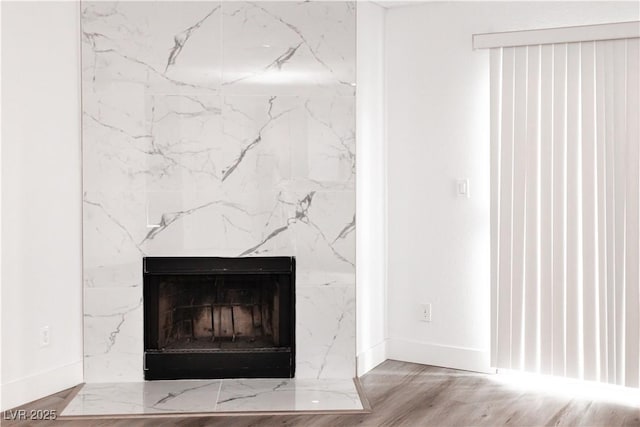 detailed view of baseboards, a fireplace, and wood finished floors