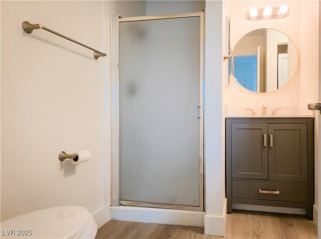 bathroom with wood finished floors, a shower stall, and toilet