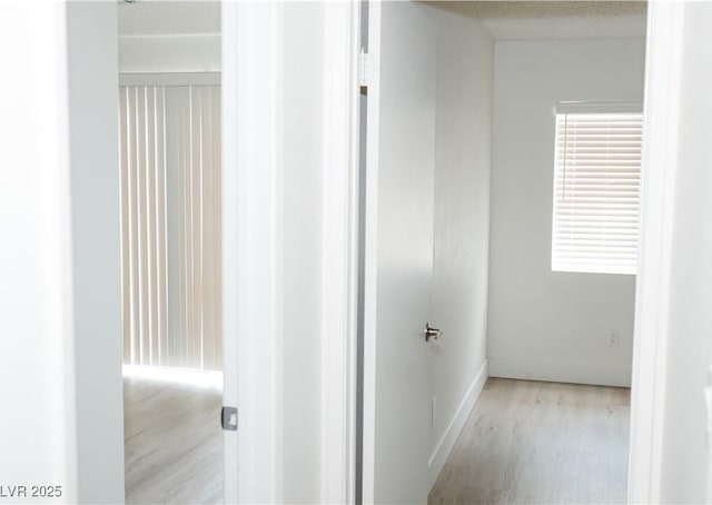 hallway with light wood-style flooring and baseboards