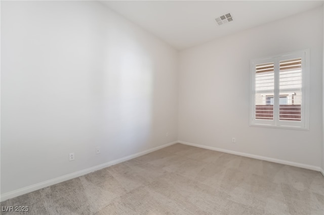 spare room featuring light colored carpet and baseboards
