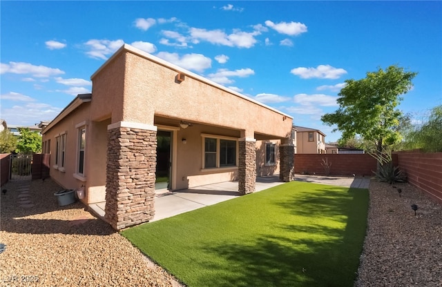 rear view of property featuring stucco siding, a fenced backyard, a patio, and stone siding