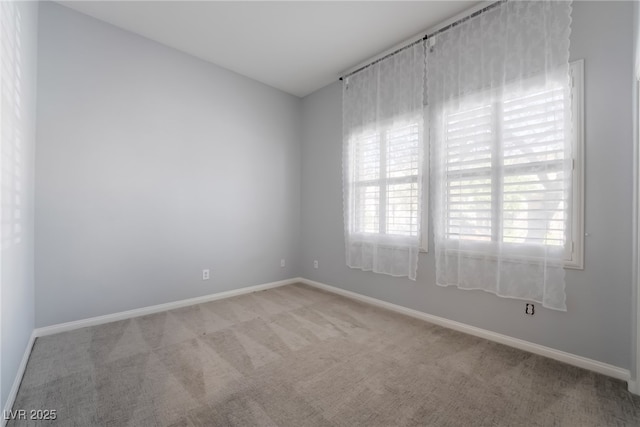empty room featuring carpet and baseboards