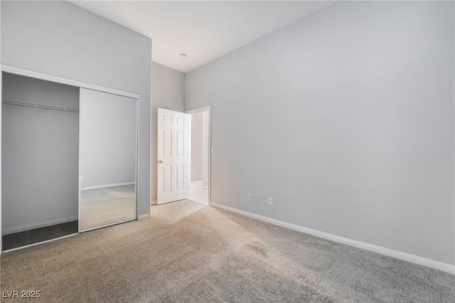 unfurnished bedroom with carpet, a closet, and baseboards