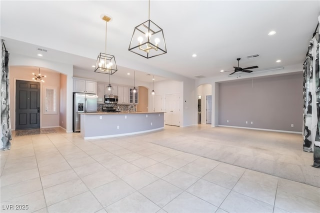 unfurnished living room with arched walkways, a chandelier, light tile patterned floors, recessed lighting, and ceiling fan