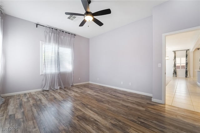 unfurnished room with a ceiling fan, healthy amount of natural light, wood finished floors, and baseboards